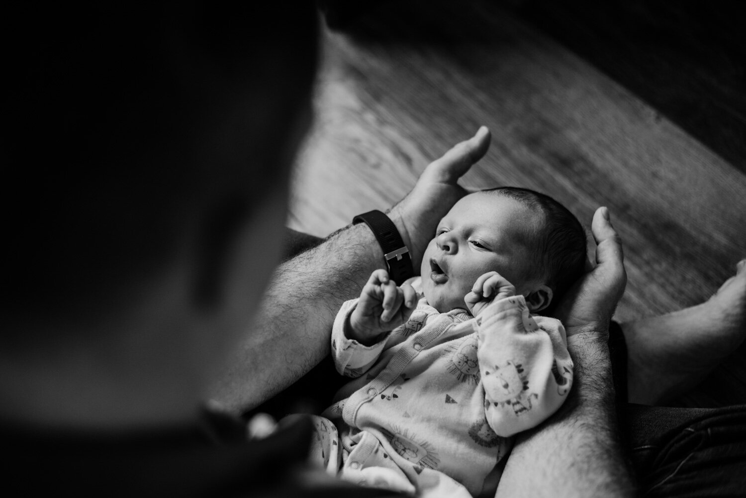 Dad cradles his newborn son's head in his hands