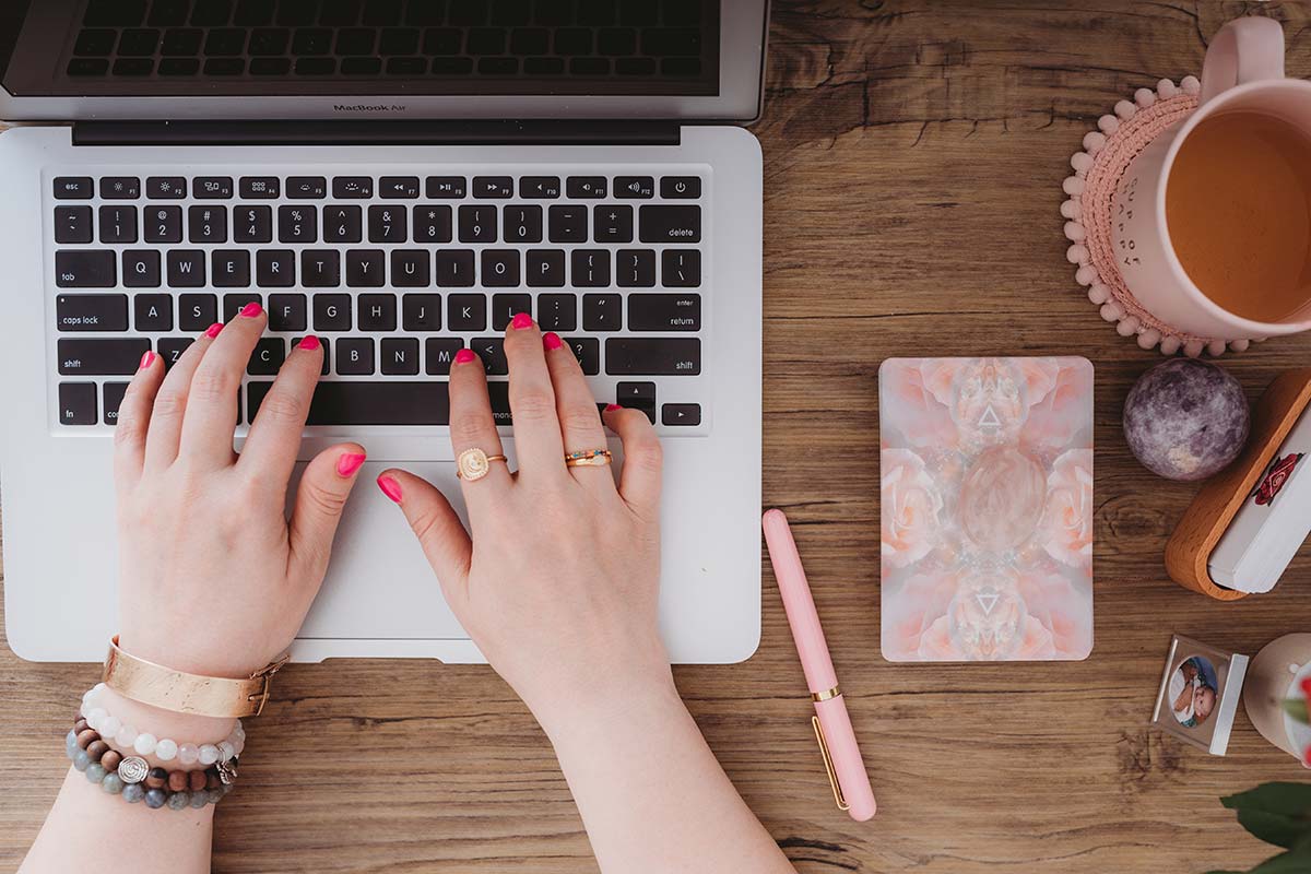 woman with pink nails typing on laptop