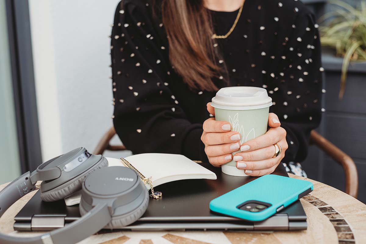 woman holding coffee cup with podcast equipment on table