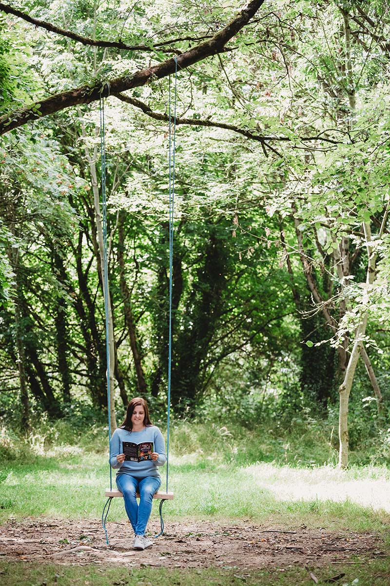 woman sitting on swing attached to large tree in the forrest lots of greenery