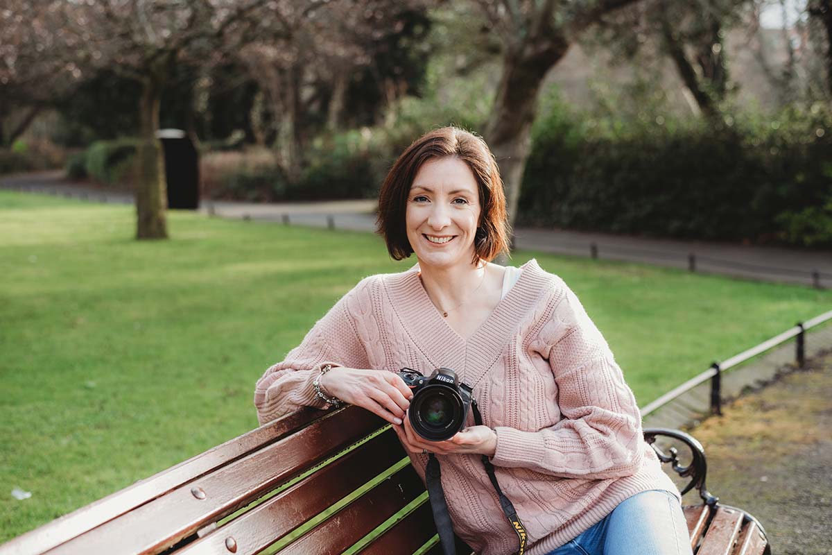 female photographer sitting on park bench in St Stephens Green holding her camera