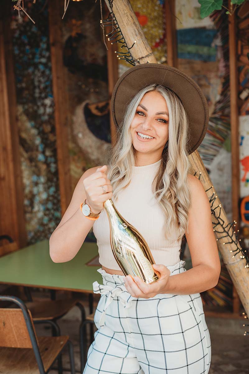 woman holding gold champagne bottle in trendy cafe