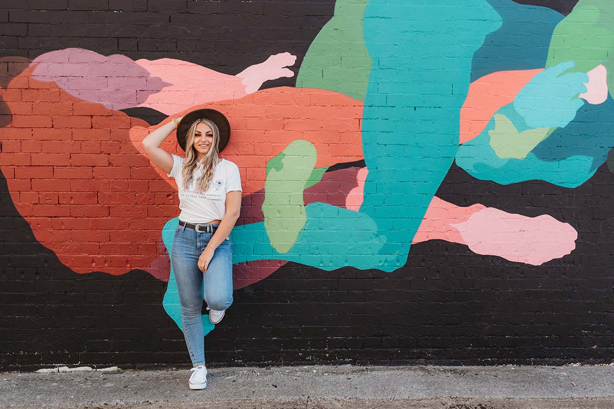 young woman leaning against wall with colourful street art