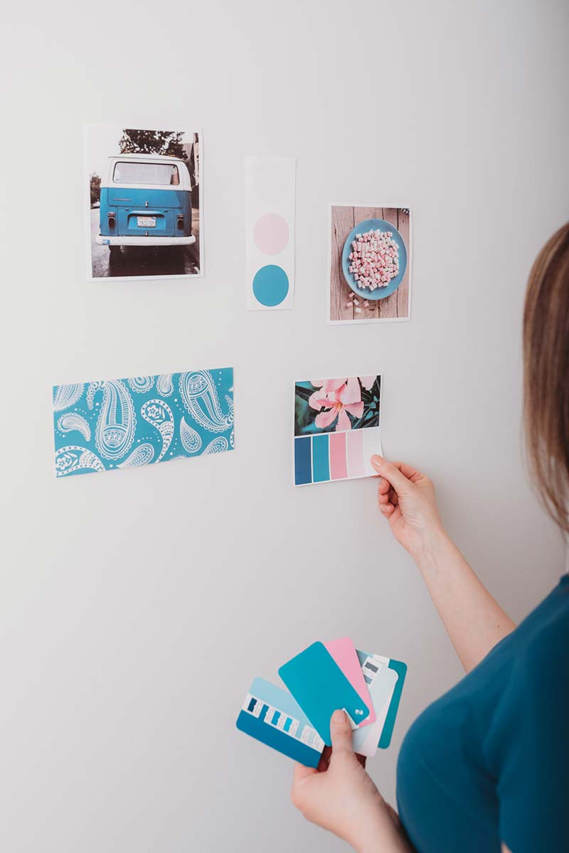 woman creating mood board sticking inspiration to wall blues and pinks