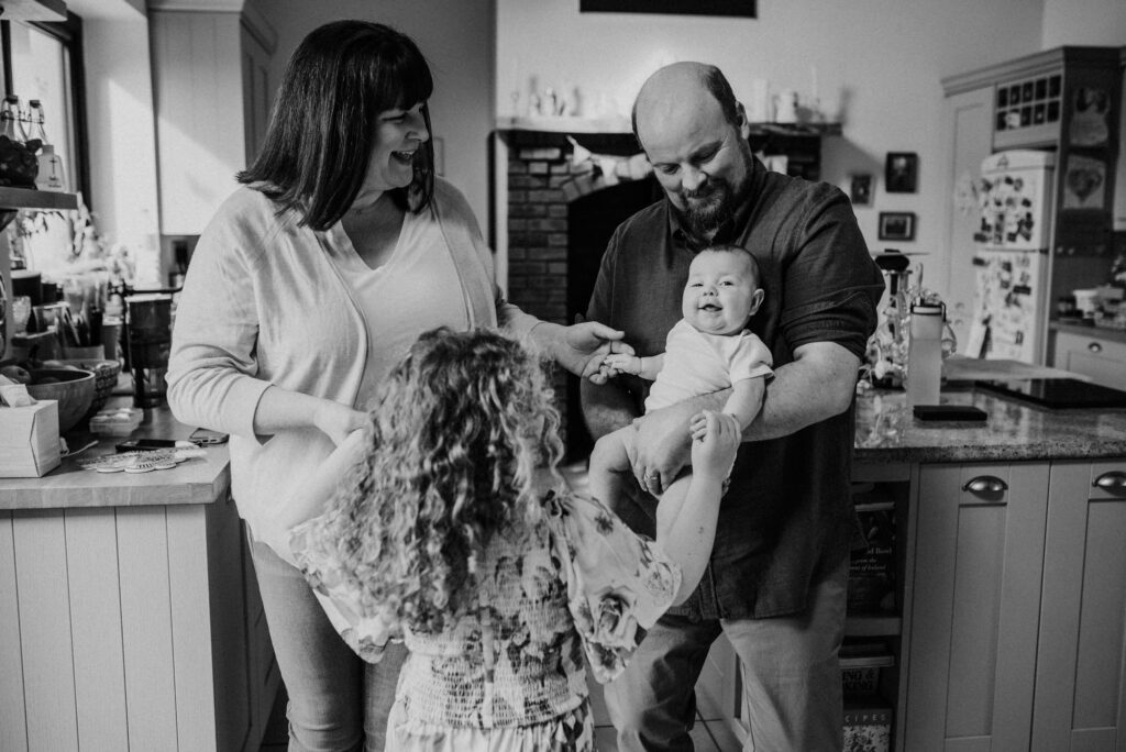 Family of four dancing in their kitchen during an in home family photoshoot.